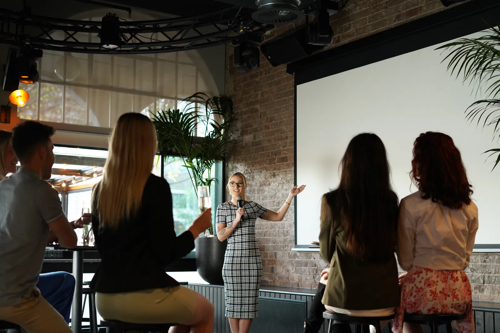 Speaker presenting to an audience in front of a projector screen at a corporate event in Canberra