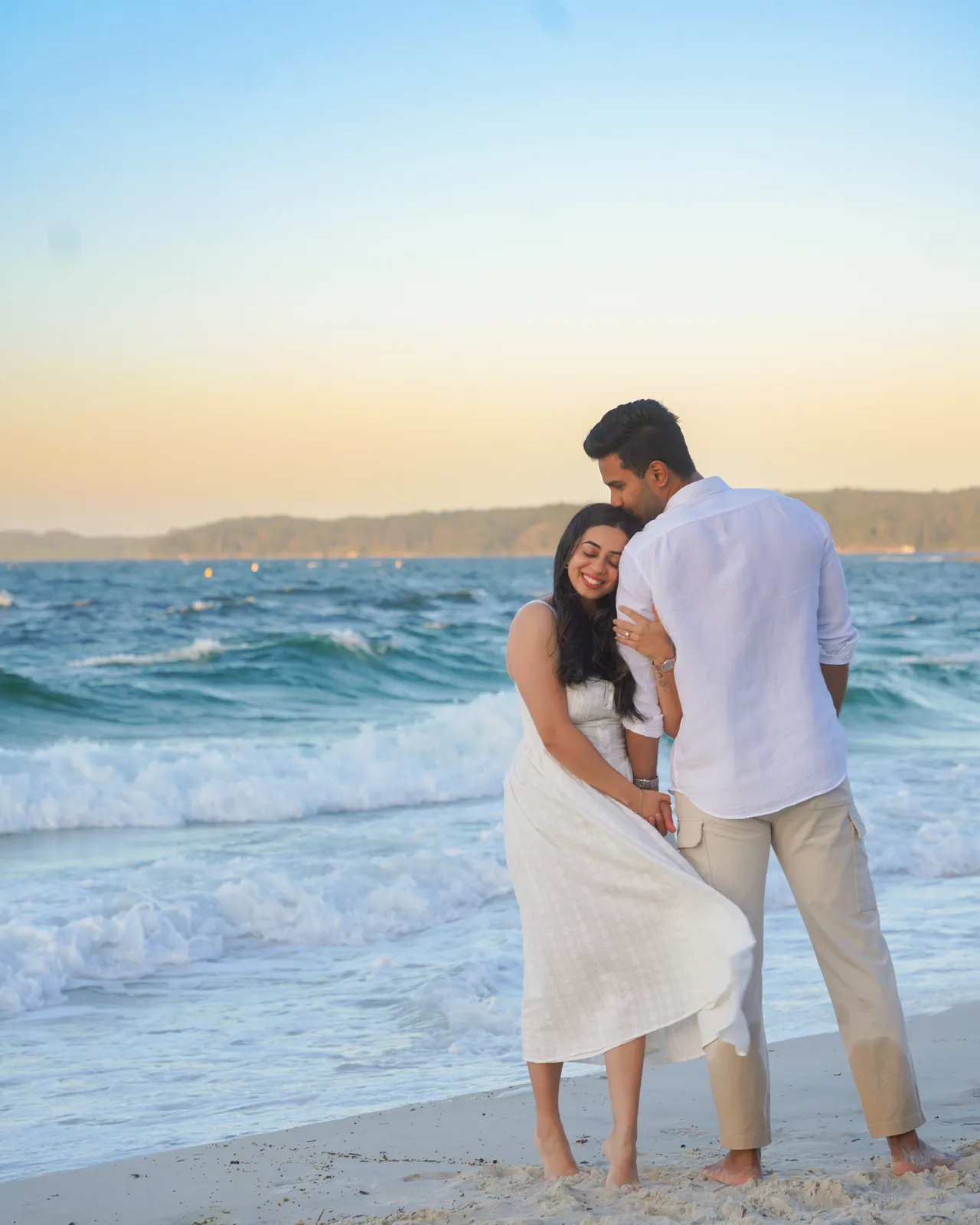 Pre-wedding portrait of a couple embracing on the beach at golden hour